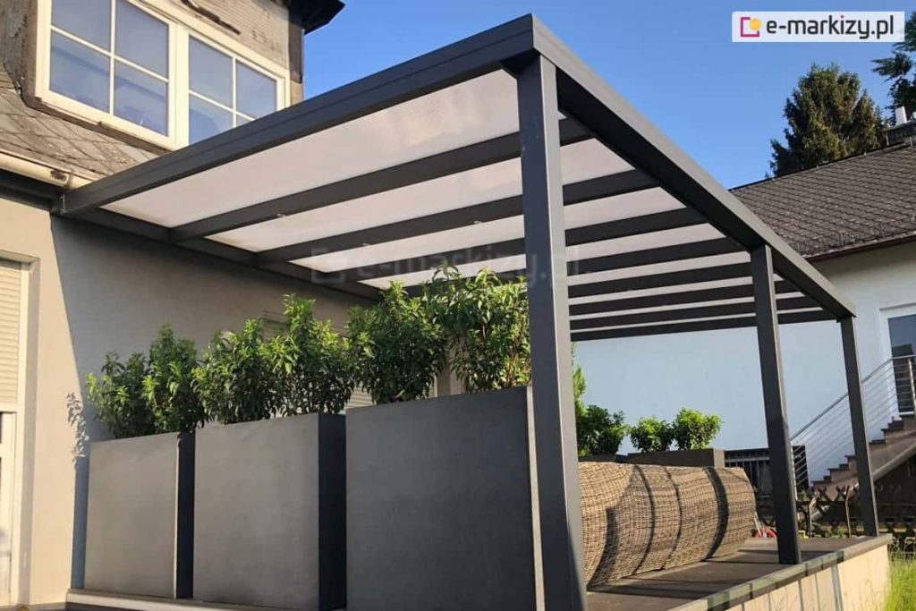 Zadaszenie tarasu Modes z dachem poliwęglanowym i oświetleniem punktowym LED nad ratanowym zestawem wypoczynkowym