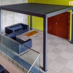 Zadaszenie tarasowe SB 350 Selt z zamkniętym dachem ustawione na tarasie w pobliżu schodów przy żółtej ścianie