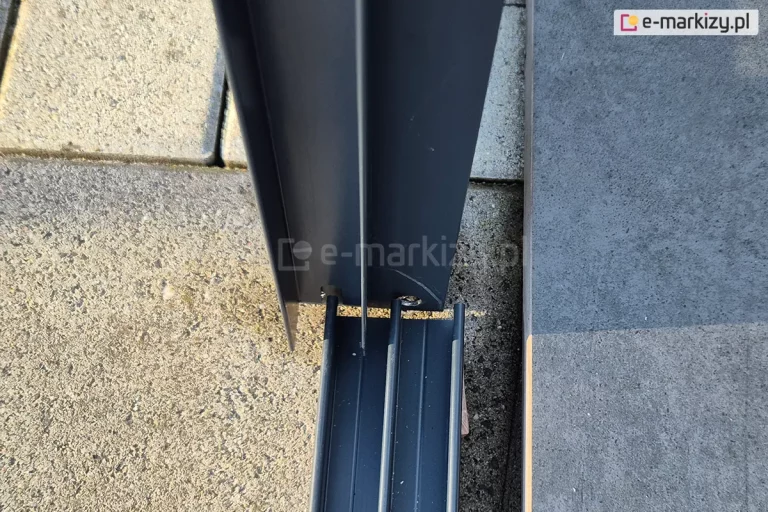 Elementy konstrukcji systemu szklanych ścian przesuwnych ramowych Sotro: prowadnica dolna i profil boczny U wykonane w kolorze antracytowym i zamocowane na betonowym tarasie do antracytowego zadaszenia.