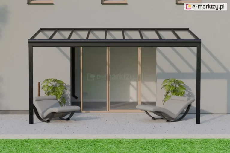 Na zdjęciu widoczny jest nowoczesny taras przylegający do jasnoszarej elewacji budynku mieszkalnego. Zadaszenie tarasu wykonane jest z ciemnej, metalowej aluminiowej konstrukcji wspierającej za pomocą dwóch skrajnych podpór przeźroczysty dach z tworzywa lub szkła, przez który przechodzą promienie słoneczne, rzucając cienie belek na ścianę budynku. Pod zadaszeniem znajduje się para identycznych, nowoczesnych leżaków z szarą tapicerką i zakrzywioną, czarną podstawą typu kołyskowego. Każdy leżak ustawiony jest przy jednej z bocznych krawędzi tarasu, obok dużej donicy z zieloną rośliną ozdobną o szerokich liściach. W tle znajduje się przeszklone, przesuwne drzwi z jasnego drewna prowadzące do wnętrza domu. Przed tarasem widać jasnoszarą, gładką posadzkę, a dalej niewielki pas żywozielonego trawnika.