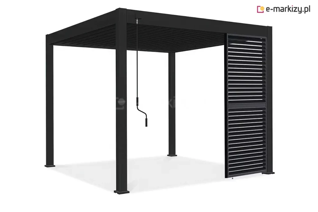 Nowoczesna wolnostojąca pergola tarasowa w kolorze antracytowym lub czarnym zaprezentowana na czystym białym tle. Konstrukcja opiera się na czterech solidnych pionowych słupach o kwadratowym przekroju, które stabilnie przylegają do podłoża za pomocą kwadratowych stóp montażowych. Górną część obiektu stanowi płaski dach z systemem ruchomych lameli, które są ułożone gęsto i równolegle, tworząc szczelną płaszczyznę zadaszenia. Po lewej stronie przedniej belki konstrukcyjnej zamocowana jest długa, pionowa korba manualna z ergonomicznym czarnym uchwytem, przeznaczona do regulacji kąta otwarcia lameli dachowych. Prawy bok pergoli został częściowo osłonięty pionowym panelem przeciwsłonecznym o strukturze żaluzjowej, składającym się z poziomych listew. Panel ten zajmuje około jednej trzeciej szerokości bocznego przęsła i sięga od górnej ramy aż do samej ziemi. Cały produkt charakteryzuje się matowym wykończeniem i surową, geometryczną formą. Pod konstrukcją widoczny jest subtelny cień rzucony na białą powierzchnię, podkreślający trójwymiarowość obiektu.