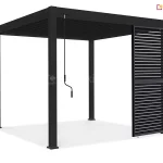 Nowoczesna wolnostojąca pergola tarasowa w kolorze antracytowym lub czarnym zaprezentowana na czystym białym tle. Konstrukcja opiera się na czterech solidnych pionowych słupach o kwadratowym przekroju, które stabilnie przylegają do podłoża za pomocą kwadratowych stóp montażowych. Górną część obiektu stanowi płaski dach z systemem ruchomych lameli, które są ułożone gęsto i równolegle, tworząc szczelną płaszczyznę zadaszenia. Po lewej stronie przedniej belki konstrukcyjnej zamocowana jest długa, pionowa korba manualna z ergonomicznym czarnym uchwytem, przeznaczona do regulacji kąta otwarcia lameli dachowych. Prawy bok pergoli został częściowo osłonięty pionowym panelem przeciwsłonecznym o strukturze żaluzjowej, składającym się z poziomych listew. Panel ten zajmuje około jednej trzeciej szerokości bocznego przęsła i sięga od górnej ramy aż do samej ziemi. Cały produkt charakteryzuje się matowym wykończeniem i surową, geometryczną formą. Pod konstrukcją widoczny jest subtelny cień rzucony na białą powierzchnię, podkreślający trójwymiarowość obiektu.