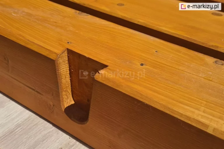 Drewniana belka pergoli Juko pokryta lakierobejcą z widocznym wyżłobieniem do mocowania krokwi dachowej, ułożona na płytce tarasowej o drewnopodobnym wzorze.