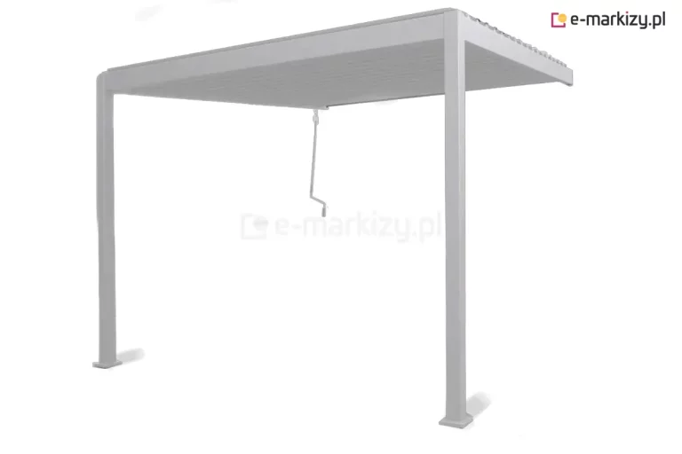 Nowoczesna pergola ogrodowa Gloria w jasnym, białym lub jasnoszarym kolorze, przedstawiona w ujęciu pod kątem na czystym białym tle. Zdjęcie prezentuje konstrukcję wspartą na smukłych, pionowych słupach z płaskim zadaszeniem lamelowym, które w tym ujęciu pozostaje zamknięte, tworząc jednolitą i szczelną płaszczyznę chroniącą przed opadami i słońcem. Charakterystycznym elementem jest umieszczona przy mocowaniu ściennym, pod dachem pergoli, biała korba sterująca, która zwisa pionowo, umożliwiając wygodną regulację ustawienia zadaszenia. Konstrukcja jest całkowicie otwarta z boków, co eksponuje jej minimalistyczny profil i precyzyjne łączenia aluminiowych elementów malowanych proszkowo. Jasna kolorystyka nadaje pergoli lekkości i sprawia, że idealnie komponuje się z nowoczesnymi elewacjami budynków oraz jasnymi meblami tarasowymi.