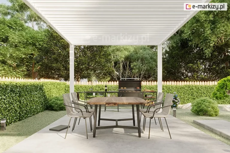 Białe aluminiowe zadaszenie tarasowe z ruchomymi lamelami Marlo zainstalowane w ogrodzie na betonowej posadzce. Konstrukcja zadaszenia opiera się na smukłych białych słupach, a dach składa się z gęsto rozmieszczonych lamel ustawionych w pozycji zamkniętej, tworząc jednolitą osłonę. Pod pergolą znajduje się drewniany stół z ciemnymi metalowymi nogami, wokół którego ustawiono cztery nowoczesnych krzeseł z szarym siedziskiem i metalowymi podłokietnikami. W tle widoczna jest zewnętrzna kuchnia z czarnym grillem i półkami na drewno, ustawiona przy drewnianym płocie i wysokim, zielonym żywopłocie. Całość kompozycji dopełnia gęsta roślinność ogrodowa z krzewami i drzewami o intensywnych zielonych liściach.