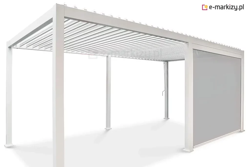 Wolnostojąca pergola bioklimatyczna Gloria o konstrukcji modułowej wykonana z aluminium w kolorze białym przedstawiona na jednolitym jasnym tle. Produkt składa się z dwóch połączonych segmentów wspartych na sześciu pionowych słupach o kwadratowym przekroju z widocznymi stopami montażowymi. Zadaszenie tworzy system poziomych ruchomych lameli aluminiowych w kolorze białym, które są ustawione w pozycji otwartej. Jeden z bocznych modułów pergoli został wyposażony w zintegrowaną roletę pionową typu screen w kolorze jasnoszarym, która jest całkowicie rozwinięta i osłania przestrzeń między dwoma słupami. Przy jednym ze słupów widoczna jest metalowa korba służąca do manualnej regulacji kąta nachylenia lameli dachowych. Całość konstrukcji charakteryzuje się minimalistycznym, nowoczesnym designem z ukrytymi systemami odprowadzania wody wewnątrz profili.