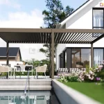 Brązowo-szara (taupe) lamelowa pergola tarasowa - model Marlo zamontowana na nowoczesnym, jasnym tarasie przy białym budynku mieszkalnym o prostej bryle. Konstrukcja pergoli opiera się na sześciu pionowych słupach o kwadratowym przekroju, wspierających ramę z ruchomymi lamelami dachowymi, które na zdjęciu są częściowo otwarte. Pod pergolą znajduje się strefa wypoczynkowa z nowoczesnym stołem jadalnianym, kremowymi krzesłami o ażurowym splocie oraz szarą sofą ogrodową umieszczoną w głębi pod zadaszeniem. Taras jest wielopoziomowy, wykonany z jasnoszarych płyt betonowych, a bezpośrednio przed nim znajduje się basen z widoczną metalową drabinką. W otoczeniu widać starannie wypielęgnowany trawnik, niską roślinność ozdobną z różowymi kwiatami oraz inne nowoczesne domy jednorodzinne w tle pod bezchmurnym, błękitnym niebem.