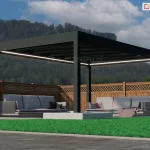 Wolnostojąca altana ogrodowa Spekta Glass o geometrycznej konstrukcji wykonanej z profili aluminiowych w kolorze głębokiej czerni. Rama nośna opiera się na czterech masywnych słupach o przekroju kwadratowym, a jej płaski dach posiada wypełnienie z dużych tafli szkła, które zapewniają ochronę przed opadami bez ograniczania dopływu światła. Wzdłuż wewnętrznych krawędzi konstrukcji zainstalowano system liniowego oświetlenia LED, emitujący ciągły pas intensywnego, białego światła. Pod zadaszeniem zorganizowano strefę wypoczynkową z dwiema dużymi sofami ogrodowymi w kolorze jasnoszarym, wyposażonymi w miękkie poduchy oraz dekoracyjny, różowy koc. Podłoże pod altaną stanowią gładkie, jasnoszare płyty tarasowe, które kontrastują z otaczającym je żywozielonym, krótko przystrzyżonym trawnikiem. W bezpośrednim sąsiedztwie słupów wkomponowano niskie, białe donice o geometrycznym kształcie, wypełnione drobnym, jasnym kruszywem. Tło kompozycji stanowi wysokie, drewniane ogrodzenie panelowe z ozdobnym, ażurowym wykończeniem w górnej części, za którym rozciąga się widok na zalesione wzgórze pod błękitnym niebem. Całość realizacji charakteryzuje się nowoczesnym designem i wysoką estetyką, tworząc luksusowe miejsce do rekreacji.