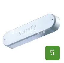 Czujnik wstrząsowy marki Somfy przeznaczony do montażu na markizach tarasowych, ukazany na białym tle. Urządzenie posiada podłużną, owalną obudowę o minimalistycznym, białym wykończeniu z widocznym na powierzchni tłoczonym logotypem producenta. W prawym dolnym rogu zdjęcia umieszczono zielony kwadrat z cyfrą pięć, stanowiący element identyfikacyjny produktu.