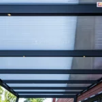 Dach zadaszenia z poliwęglanu Lunaro Bosco Deponti wykonany z antracytowej konstrukcji oraz wypełnienia z poliwęglanu komorowego z widocznymi w belkach krokwiowych punktami oświetlenia LED.