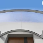 Widoczny od dołu zamocowany nad drzwiami wejściowymi niskiego budynku daszek nad drzwi o łukowym kształcie z aluminiową konstrukcją w kolorze białym oraz wypełnieniem z przejrzystego poliwęglanu komorowego. Nad budynkiem i przez płytę daszka widoczne niebieskie niebo.