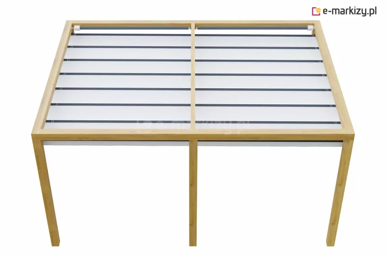 Drewniana pergola tarasowa o wydłużonej konstrukcji wykonanej z jasnego drewna świerkowego, posiadająca wzmocnienie w postaci dodatkowego, centralnego słupa wspierającego górną ramę. Wnętrze konstrukcji zostało przesłonięte system zadaszenia typu rzymskiego, wykonany z jasnego materiału podzielonego poprzecznymi listwami wzmacniającymi na równe segmenty. W obu częściach ramy dachu widoczne są rury i wały napędowe elektrycznego sterowania osłoną. Całość ujęta została w perspektywie z góry, prezentując funkcjonalne rozwiązanie pozwalające na modułowe zarządzanie zacienieniem większych powierzchni tarasowych przy zachowaniu spójnej estetyki naturalnego drewna.