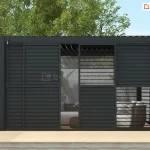 Pergola Gloria ustawiona na drewnianym podeście w ogrodzie z widocznym w tle białym murkiem i drzewami posiada przesłonięte czarnymi panelami lamelowymi przesuwnymi ściany frontowe. Przez uchylone częściowo lamele widoczne ukryte pod pergolą meble wypoczynkowe z technorattanu z białymi siedziskami.