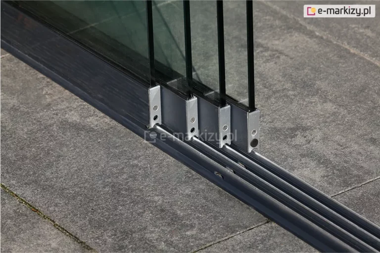 Cztery panele szklane przesuwnych drzwi Auris na taras rozsunięte na torach, dzięki czemu widoczne jest szkło każdego segmentu. Pod panelami prowadnica dolna z czterema torami zamocowana do betonowych płytek podłoża.