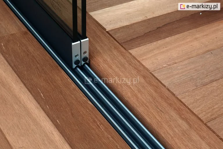 Zamocowana w drewnianej podłodze prowadnica dolna systemu Auris z trzema torami. Wykorzystane zostały tylko dwa tory, na których zainstalowano panele szklane.