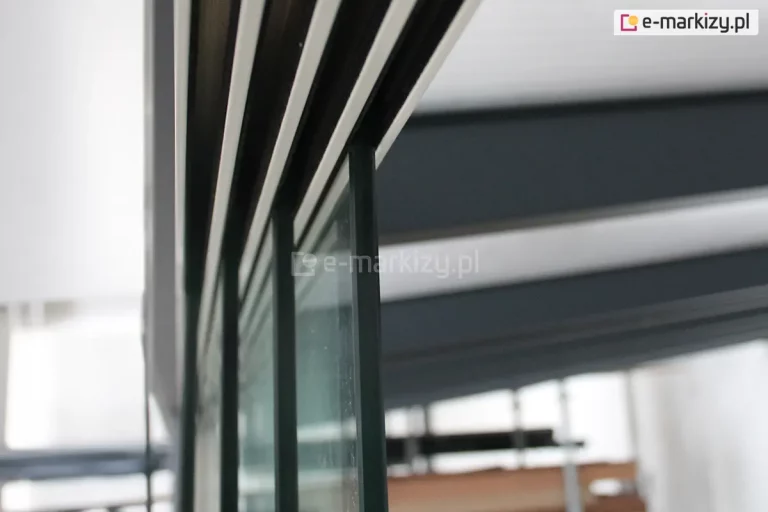 Górna prowadnica systemu przesuwnego Auris z widocznymi zamocowanymi w niej, rozsuniętymi czterema panelami szklanymi grubości 10 mm.