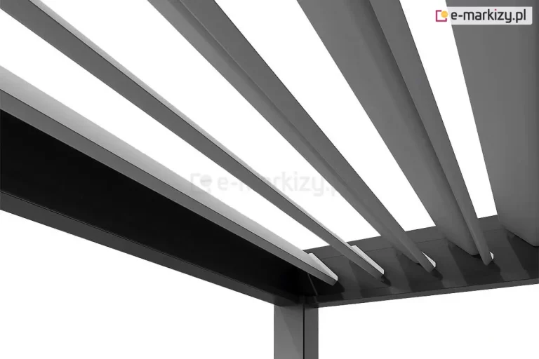 Zdjęcie przedstawia zbliżenie na system zadaszenia pergoli tarasowej Marlo, koncentrując się na detalach ruchomych lameli. Widoczna jest wewnętrzna część aluminiowej ramy w kolorze ciemnego antracytu, w której osadzone są poprzeczne pióra dachu (lamele) w kontrastującym, jasnoszarym odcieniu. Lamele są uchylone pod kątem, co demonstruje mechanizm regulacji dopływu światła. Każda lamela ma aerodynamiczny, lekko zaokrąglony kształt i jest zamocowana do bocznej szyny za pomocą dyskretnych punktów obrotu. Perspektywa od dołu podkreśla precyzję spasowania elementów oraz nowoczesne, dwukolorowe wykończenie konstrukcji, które ułatwia rozjaśnienie przestrzeni pod zadaszeniem.