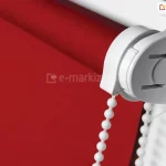 Roletka mini zawieszona na skrzydle okna z białym mechanizmem i soczyście czerwoną tkaniną przeciwsłoneczną.