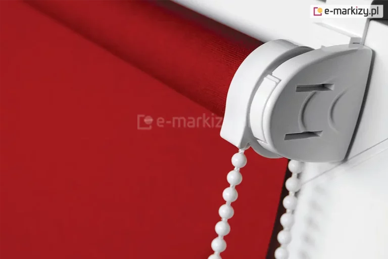 Roletka mini zawieszona na skrzydle okna z białym mechanizmem i soczyście czerwoną tkaniną przeciwsłoneczną.