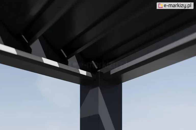 Zbliżenie na węzeł konstrukcyjny dachu nowoczesnej pergoli aluminiowej Rubio w kolorze antracytowym. Zdjęcie wykonane z żabiej perspektywy (od dołu) ukazuje miejsce styku pionowego słupa nośnego o kwadratowym przekroju z dwiema poziomymi belkami ramy głównej, w których dolnej części widoczne są białe listwy oświetlenia ledowego. Powyżej ramy widoczne są ruchome lamele dachowe ustawione pod kątem. Konstrukcja charakteryzuje się minimalistycznym designem z niewidocznymi łączeniami śrubowymi, co podkreśla estetykę premium. Belki posiadają zintegrowany system rynnowy do odprowadzania wody deszczowej. W tle widoczne jest jasne, bezchmurne niebo, a na powierzchni profili aluminiowych zauważalne są subtelne refleksy świetlne oraz gra cieni wynikająca z geometrii obiektu.