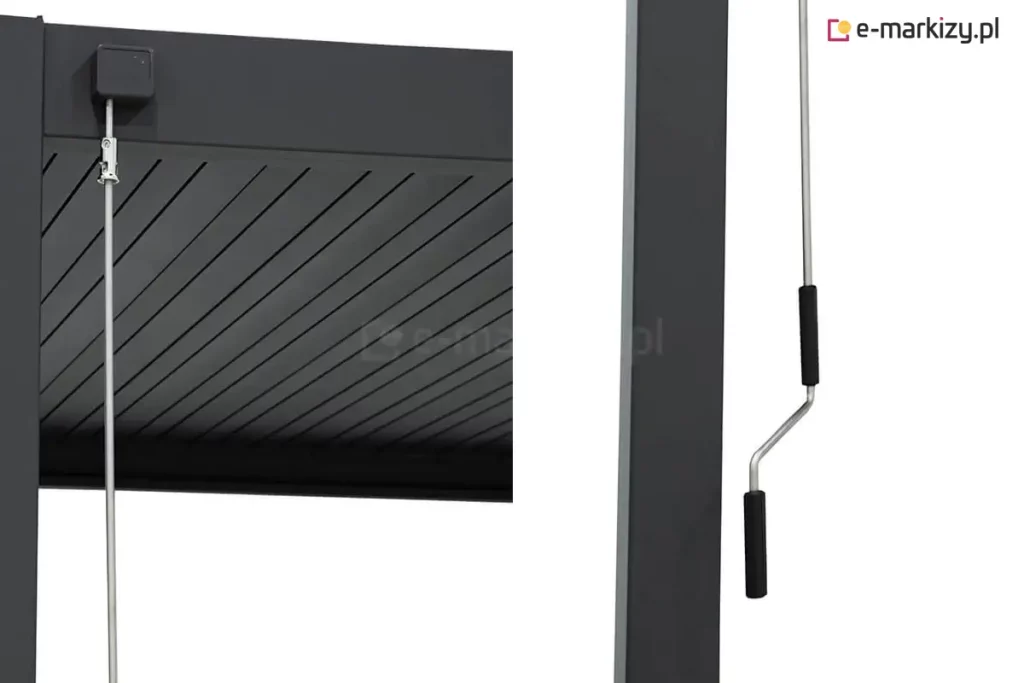 Zbliżenie na mechanizm sterowania korbowego nowoczesnej pergoli tarasowej Gloria w kolorze antracytowym. Po lewej stronie widoczny jest górny detal konstrukcji: kwadratowy przegub zamontowany na ramie, do którego podpięty jest metalowy drążek za pomocą srebrnego zaczepu. W tle widoczne są aluminiowe lamele dachu pergoli. Po prawej stronie zdjęcia, obok słupa pergoli, znajduje się dolna część drążka zakończona wygiętą korbą z dwoma czarnymi, ergonomicznymi uchwytami z tworzywa sztucznego, służąca do ręcznego obracania piór dachu. Całość konstrukcji charakteryzuje się matowym wykończeniem i minimalistycznym designem.