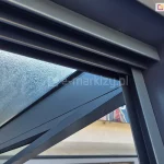 Zbliżenie na połączenie prowadnicy górnej oraz bocznego profilu doszczelniającego U. Całość wykonana w kolorze dopasowanym do kolorystyki zadaszenia ze szkłem.