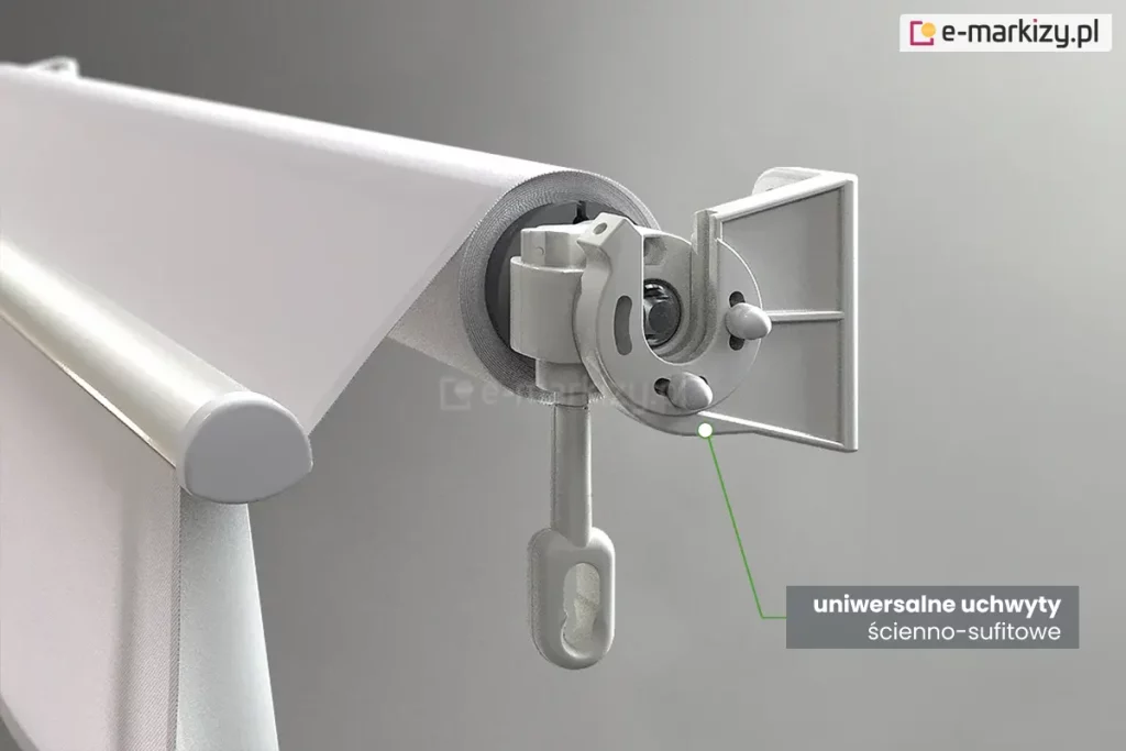 Zbliżenie techniczne na system mocowania markizy balkonowej Italia, prezentujące uniwersalne uchwyty ścienno-sufitowe. Na zdjęciu widoczna jest boczna głowica markizy w kolorze jasnoszarym, zamontowana w odlewanym, aluminiowym uchwycie o budowie modułowej. Konstrukcja uchwytu posiada prostopadłe płaszczyzny z otworami, co pozwala na jego przykręcenie zarówno do pionowej ściany, jak i poziomego sufitu. W centralnej części detalu widoczna jest przekładnia z wyciągniętym pionowo w dół plastikowym uchem, służącym do obsługi za pomocą korby. Belka nawojowa z nawiniętą jasną tkaniną jest stabilnie osadzona w gnieździe uchwytu. Po prawej stronie u dołu znajduje się szary prostokąt z białym napisem informacyjnym, od którego zielona linia prowadzi do punktu styku głowicy z uchwytem, podkreślając precyzję dopasowania elementów. W tle widoczna jest również przednia belka obciążająca z zaokrągloną zaślepką boczną.