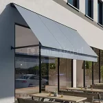 Markiza Italia Selt w kasecie z niebieską tkaniną nad witryną kawiarni i stolikami dla klientów