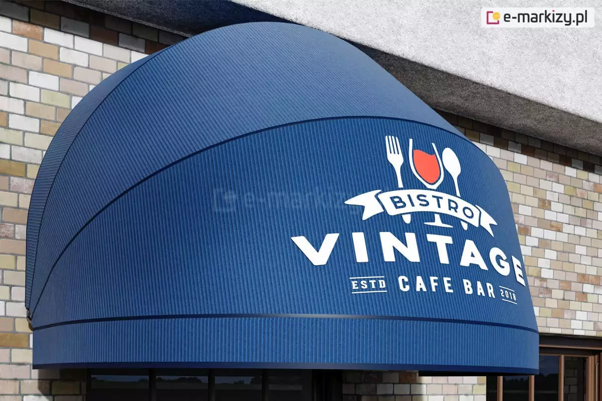 Półokrągła markiza koszowa zamocowana na ścianie z jasnych cegieł wyposażona w granatowe poszycie oraz prostą falbanę. Na pierwszym polu nad falbaną duży nadruk logo "Bistro vintage".