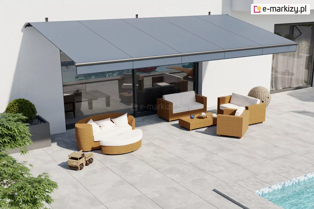 Widok z góry na rozłożystą markizę Australia o grafitowym, jednolitym poszyciu, która została zamontowana na białej ścianie nowoczesnego budynku. Konstrukcja markizy Australia opiera się na solidnych uchwytach mocowanych do elewacji, a jej tkanina jest idealnie napięta, tworząc szeroki pas cienia nad strefą wypoczynkową. Pod osłoną markizy znajduje się zestaw mebli ogrodowych wykonanych z jasnobrązowej plecionki, składający się z dwuosobowej sofy, dwóch foteli, niskiego stolika kawowego oraz okrągłej leżanki z białymi materacami i poduszkami. Taras wyłożony jest dużymi, kwadratowymi płytami w kolorze jasnoszarym, na których w pełnym słońcu widoczna jest również drewniana zabawka w kształcie ciężarówki. W dolnym prawym rogu zdjęcia widać fragment błękitnej tafli basenu wyłożonego drobną mozaiką, a po lewej stronie ciemną donicę z formowaną roślinnością. Markiza Australia skutecznie zasłania duże przeszklenia przesuwne prowadzące do wnętrza domu, chroniąc pomieszczenia przed nagrzewaniem i tworząc komfortowe miejsce do relaksu na świeżym powietrzu.