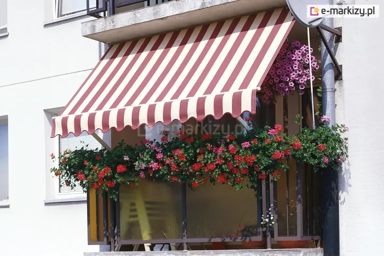 Klasyczny balkon w bloku mieszkalnym, udekorowany obfitymi kompozycjami kwiatowymi i osłonięty tradycyjną markizą balkonową z ramionami poręczowymi. Markiza posiada poszycie w szerokie, pionowe pasy w kolorach bordowym i kremowym, wykończone na dole dekoracyjną, pofalowaną falbaną z białą lamówką. Materiał jest rozwinięty pod skosem, tworząc stabilne zadaszenie nad całą szerokością balkonu. Balustrada balkonu jest niemal całkowicie zasłonięta przez gęste, zwisające pelargonie o intensywnie czerwonych i różowych kwiatach, które rosną w podłużnych skrzynkach. Dodatkowo, w prawym górnym rogu pod sufitem wnęki, zawieszona jest donica z bujną, różową surfinią. Balustrada posiada wypełnienie z półtransparentnych, żółtawych paneli, a po prawej stronie widoczny jest pionowy fragment rynny deszczowej oraz zamontowana na elewacji antena satelitarna. Ściana budynku jest biała, o gładkiej strukturze, co stanowi jasne tło dla nasyconych barw kwiatów i pasiastej tkaniny osłonowej. Całość przedstawia przytulną i zadbaną przestrzeń rekreacyjną w pełnym świetle dziennym.