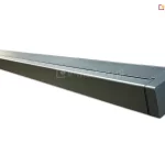 Widok od boku na złożoną markizę w charakterystycznej kwadratowej kasecie - model Quadra MOL. Markiza posiada antracytową konstrukcję, lekko połyskującą w świetle padającym na jej lewy, oddalony koniec, mocowania do ściany oraz ukazana została na białym tle.