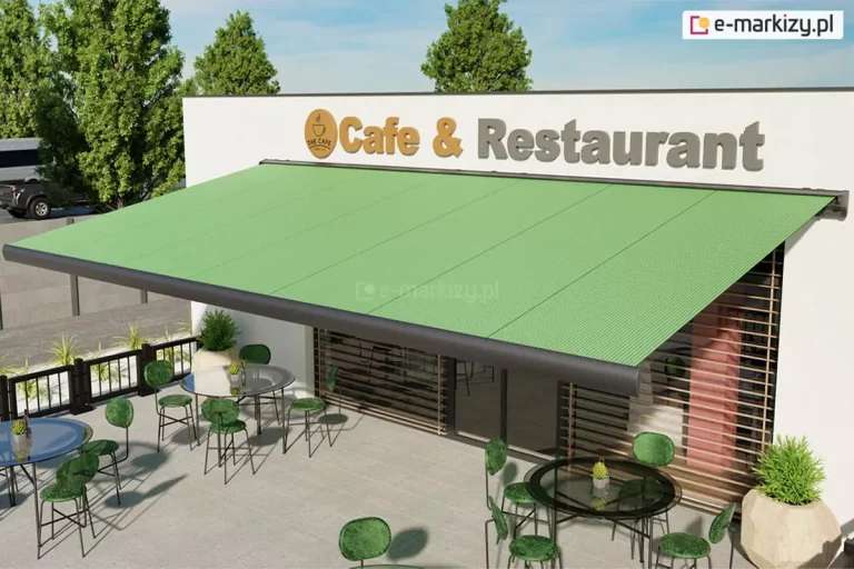 parterowy budynek o jasnej fasadzie z dużym szyldem "Cafe & Restaurant" pod którym zamocowano markizę Palladio z konstrukcją o srebrzystografitowym kolorze oraz zieloną tkaniną poszycia. Markiza zacienia wejście do restauracji, a pod nią rozstawiono stoliki z zielonymi krzesełkami. Ponad budynkiem widoczne drzewa oraz niebo.
