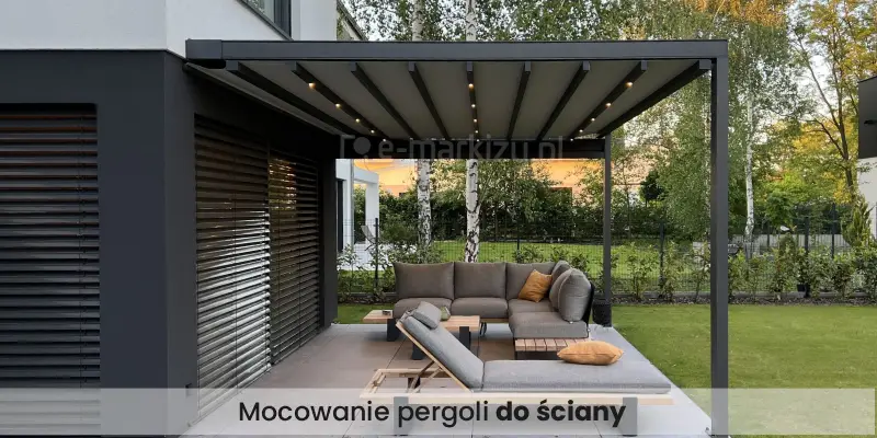 Nowoczesny taras zadaszony pergolą Square Flat, przylegający do nowo wybudowanego domu jednorodzinnego o prostych, geometrycznych formach. Zadaszenie tworzy prostokątna, metalowa konstrukcja w grafitowym kolorze, oparta na dwóch słupach. Dach pergoli jest rozsunięty, z widocznymi poprzecznymi belkami i umieszczonym między nimi jasnym poszyciem i wbudowanym oświetleniem LED, które jest włączone. Pod pergolą znajduje się duży, narożny zestaw wypoczynkowy – sofa modułowa z szarej tkaniny, z szerokimi oparciami i poduszkami, ustawiona na drewniano-metalowej ramie. Na sofie i leżance widoczne są ozdobne poduszki w odcieniu musztardowym. Całość ustawiona jest na dużych, szarych płytach tarasowych. Tło stanowi ogrodzenie z siatki i wysoki żywopłot, za którym rosną białe brzozy i inne drzewa liściaste. W oddali widoczna jest nowoczesna zabudowa mieszkalna. Taras płynnie łączy się z zadbanym, zielonym trawnikiem. Po lewej stronie kadru widać ścianę budynku z dużym oknem osłoniętym poziomymi, zewnętrznymi żaluzjami. Na dole napis "Mocowanie pergoli do ściany" umieszczony na bielonym półprzejrzystym pasie.