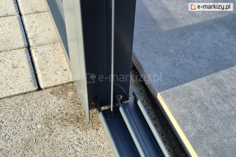 Zbliżenie miejsca mocowania prowadnicy dolnej do podpory zadaszenia. Prowadnica mocowana jest do podłoża - tutaj do betonowych płyt tarasowych.