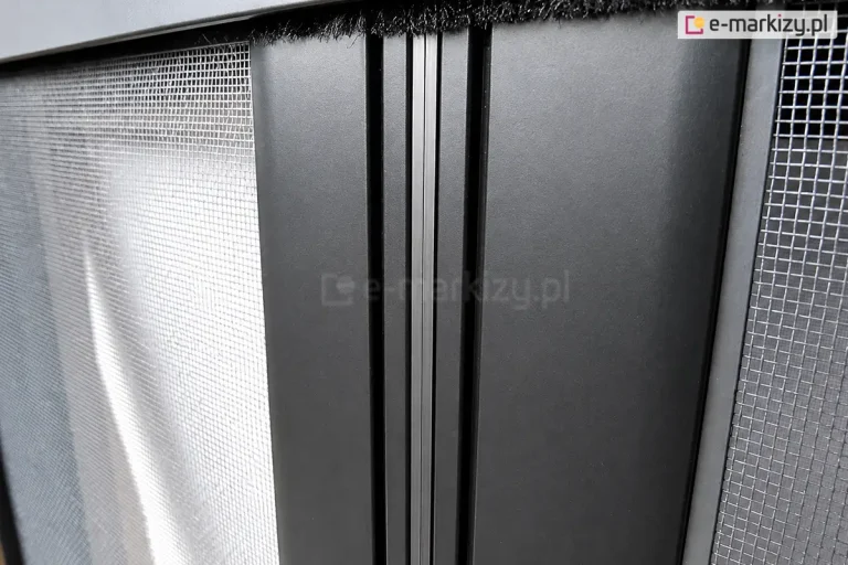 Zbliżenie magnetycznego domknięcia profili moskitiery rolowanej poziomej podwójnej w kolorze antracytu z widoczna w górnym profilu uszczelką szczotkową, która dodatkowo zabezpiecza pomieszczenie przed przedostawaniem się do wnętrza insektów.