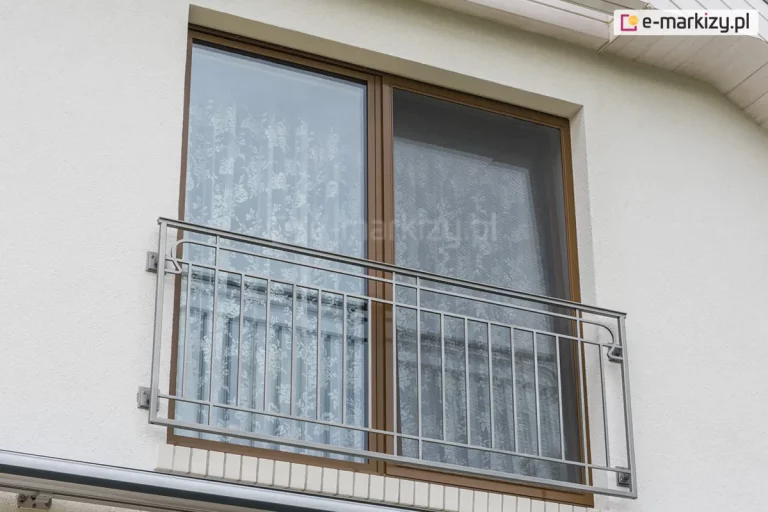 Moskitiera przesuwna Solid z jednym panelem z siatką umieszczona na brązowym oknie balkonowym z francuskim balkonem. Nad oknem widoczna podbitka dachu w białym kolorze. Okno dodatkowo od środka pomieszczenia przesłonięto firanką w różany wzór.