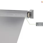 Przekrój techniczny bocznej części markizy balkonowej Italia, prezentujący napęd elektryczny w belce nawojowej. Zdjęcie przedstawia zbliżenie na prawą stronę górnej rury nawojowej, która jest wykonana z półprzezroczystego materiału (efekt rentgena), aby uwidocznić wewnętrzny silnik rurowy. Silnik jest osadzony wewnątrz stalowej rury, a jego głowica z widocznym mechanizmem zębatym styka się z bocznym uchwytem mocującym. Uchwyt ścienno-sufitowy w kolorze szarym posiada otwory montażowe i stabilizuje całą oś obrotu. Z belki nawojowej wysunięte jest gładkie, jasnoszare poszycie tkaniny. Po prawej stronie zdjęcia umieszczono szary prostokątny boks z białym napisem informacyjnym, od którego odchodzą dwie zielone linie wskazujące bezpośrednio na umiejscowienie napędu wewnątrz konstrukcji.