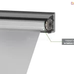 Przekrój techniczny prawej strony kasety markizy w kolorze antracytowym, prezentujący mechanizm wewnętrzny. Zdjęcie przedstawia aluminiową belkę nawojową, na którą nawinięty jest fragment jasnoszarego materiału poszycia. Widoczny jest detal konstrukcyjny zakończenia rury nawojowej z zamontowanym wewnątrz silnikiem. Od mechanizmu odchodzi zielona linia wskazująca na szary prostokąt z napisem informacyjnym: „napęd elektryczny w belce nawojowej”. Konstrukcja kasety ma nowoczesny, kanciasty kształt. Tło obrazu jest jednolite i białe.