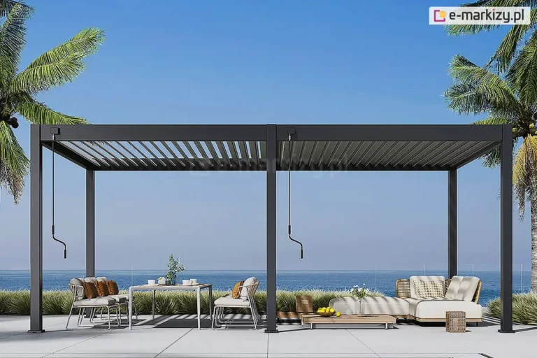 Nowoczesna szeroka pergola lamelowa Marlo z dwoma niezależnymi sekcjami dachu lamelowego, każdą sterowaną oddzielną korbą, ustawiona została na przestronnym tarasie z widokiem na morze oraz palmami po bokach i zakończonym trawami od strony wody. Pod lewą częścią pergoli ustawiono duży stół z naczyniami oraz krzesła z poduszkami. Po prawej stronie, wygodny narożnik z miękkimi siedziskami, niski stolik z wazonem oraz misą cytryn. Obok narożnika ustawiono pleciony wiklinowy pojemnik na świecę.