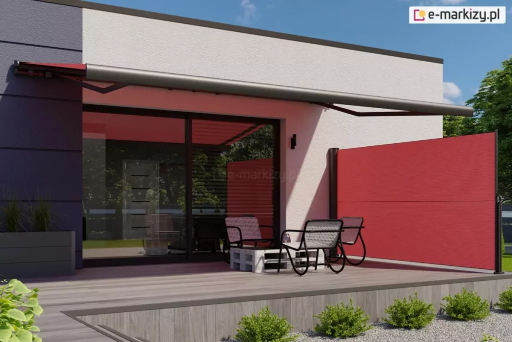 Nowoczesna wizualizacja tarasu przylegającego do budynku o minimalistycznej architekturze z płaskim dachem. Elewacja domu składa się z dwóch tekstur: białego tynku oraz ciemnoszarych, dużych płyt elewacyjnych z poziomymi boniowaniami po lewej stronie. Na tarasie zamontowano system osłon przeciwsłonecznych w intensywnym czerwonym kolorze. Głównym elementem jest szeroka markiza tarasowa kasetowa z ramionami przegubowymi, której poszycie rzuca czerwony cień na jasną ścianę budynku i przeszklenia. Konstrukcja markizy, w tym kaseta i ramiona, wykonana jest z aluminium w kolorze ciemnografitowym. Poniżej, na prawej krawędzi tarasu, znajduje się boczna markiza Bora Selt wyciągana z pionowej kasety, tworząca czerwoną ściankę oddzielającą przestrzeń wypoczynkową. Taras został wyłożony deskami kompozytowymi w kolorze jasnoszarego drewna. Na tarasie ustawiono zestaw mebli ogrodowych typu lounge, składający się z trzech nowoczesnych foteli o metalowej, czarnej konstrukcji z siatkowym siedziskiem oraz niskiego stolika kawowego wykonanego z białej palety transportowej. Duże, przesuwne drzwi tarasowe w czarnych ramy odbijają otaczającą zieleń drzew. Przed tarasem widoczna jest nowoczesna aranżacja ogrodowa z szarym żwirem, w którym posadzono w równych odstępach niskie, zielone krzewy ozdobne. Po lewej stronie znajduje się antracytowa donica z wysokimi trawami ozdobnymi. Całość przedstawiona jest w pełnym słońcu na tle bezchmurnego, niebieskiego nieba.