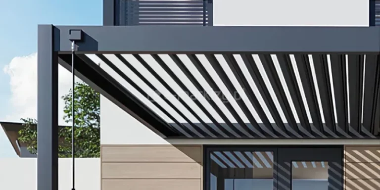 Zbliżenie na fragment konstrukcji nowoczesnej pergoli tarasowej Rubio Soft, wykonanej z aluminium w kolorze antracytowym, skupiające się na mechanizmie sterowania zadaszeniem. Zdjęcie prezentuje otwarte lamele dachowe ustawione pod kątem, co tworzy rytmiczny wzór ukośnych, równoległych pasów, przez które prześwituje jasne niebo. Na przedniej, poziomej belce ramy zamontowana jest czarna, kwadratowa puszka mechanizmu, z której wyprowadzona jest długa, pionowa korba sterująca o matowym wykończeniu. W tle widoczna jest jasna elewacja budynku z fragmentem okna oraz pionowe pasy cienia rzucane przez otwarte lamele na ścianę wykończoną drewnopodobnymi panelami. Konstrukcja charakteryzuje się ostrymi krawędziami i minimalistycznym wykończeniem, typowym dla nowoczesnej architektury ogrodowej. Perspektywa ujęcia od dołu podkreśla przestrzenną strukturę dachu oraz precyzję wykonania elementów ruchomych.