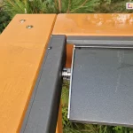 Drewniane belki pergoli, do których zamocowano profile dachu lamelowego SB400 MD Selt z umieszczonym w nim jednym lamelem dachowym w kolorze antracytowym.