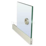 Zdjęcie przedstawia fragment panelu szklanego systemu przesuwnego Auris, zamontowanego w dolnym profilu aluminiowym w kolorze białym. Transparentna tafla szkła o wyraźnym zielonkawym odcieniu na bocznej krawędzi jest wyposażona w okrągły, metalowy uchwyt wpuszczany o satynowym wykończeniu, ułatwiający przesuwanie skrzydła. Dolna listwa profilu o gładkiej strukturze zakończona jest srebrnym elementem technicznym z widocznym wkrętem oraz otworem regulacyjnym. Całość kompozycji ukazana jest w ujęciu izometrycznym na jasnym tle, co pozwala na precyzyjne zaobserwowanie połączenia szkła, białego profilu oraz akcesoriów sterujących w systemie Auris.