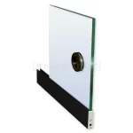 Zdjęcie przedstawia fragment panelu szklanego systemu przesuwnego Auris, osadzonego w dolnym profilu aluminiowym w kolorze czarnym. Transparentna tafla szkła o widocznym zielonkawym odcieniu na bocznej krawędzi została wyposażona w okrągły, wpuszczany uchwyt (klamkę) w kolorze czarnym, który kolorystycznie współgra z dolną listwą. Uchwyt posiada ergonomiczne wgłębienie ułatwiające przesuwanie skrzydła drzwiowego. Czarna listwa dolna o matowym wykończeniu zakończona jest srebrnym elementem technicznym, w którym znajduje się wkręt montażowy oraz otwór regulacyjny systemu jezdnego. Produkt ukazany jest pod kątem na białym tle, co podkreśla nowoczesny design i kontrast między ciemnymi elementami okucia a przezroczystością wypełnienia szklanego w systemie Auris.