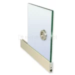 Zdjęcie prezentuje fragment panelu szklanego systemu przesuwnego Auris, zamontowanego w dolnym profilu aluminiowym w kolorze kremowo-białym. Przezroczysta tafla szkła o widocznym zielonkawym odcieniu na bocznej, oszlifowanej krawędzi została wyposażona w okrągły, wpuszczany uchwyt (klamkę) wykonany ze stali nierdzewnej lub aluminium o satynowym wykończeniu. Uchwyt znajduje się w centralnej części widocznego fragmentu szkła i posiada wgłębienie ułatwiające przesuwanie skrzydła. Dolna listwa o gładkiej, matowej powierzchni jest zakończona srebrnym elementem technicznym z widocznym wkrętem mocującym oraz otworem regulacyjnym. Całość ukazana jest w rzucie izometrycznym na jasnym tle, co pozwala na szczegółowe zaobserwowanie integracji akcesoriów z systemem jezdnym Auris.