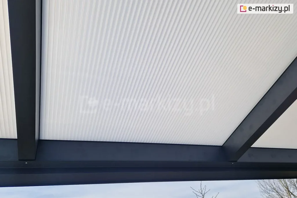 Zbliżenie na płytę z poliwęglanu komorowego w odcieniu mlecznym, zamocowaną w konstrukcji zadaszenia o antracytowym kolorze.