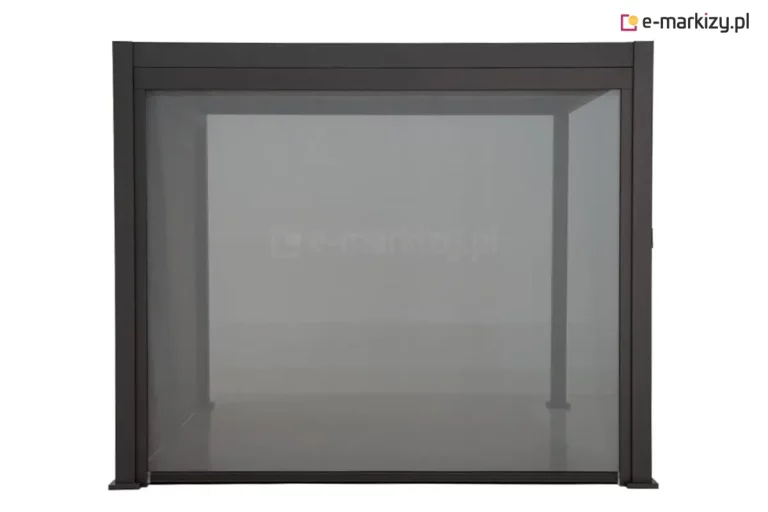 Antracytowa konstrukcja pergoli aluminiowej Gloria, wyposażoną w zintegrowaną roletę zewnętrzną typu ZIP przedstawiona na białym tle. Roleta w kolorze ciemnoszarym jest całkowicie rozwinięta, szczelnie wypełniając frontowe światło przejścia między dwoma pionowymi słupami a górną belką konstrukcyjną. Tkanina screenowa charakteryzuje się drobnym splotem, który zapewnia ochronę przed słońcem i insektami, zachowując przy tym delikatną przezierność, co pozwala dostrzec zarysy tylnych słupów pergoli. System ZIP gwarantuje precyzyjne prowadzenie materiału w bocznych szynach, co zapobiega jego wypadaniu nawet przy silnych podmuchach wiatru. Całość ma surowy, techniczny wygląd, eksponujący detale wykończenia profili oraz napięcie połaci tkaniny.