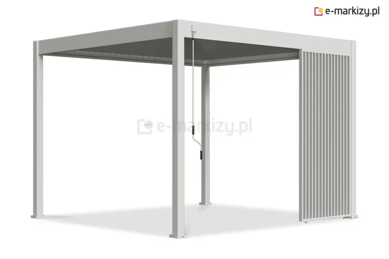 Wizualizacja nowoczesnej pergoli lamelowej Marlo w kolorze białym lub jasnoszarym, wyposażonej w stały panel narożnikowy. Konstrukcja o minimalistycznym designie składa się z czterech pionowych słupów o kwadratowym przekroju oraz płaskiego dachu z systemem ruchomych lameli, które na obrazku są całkowicie zamknięte. Po prawej stronie, między słupami, zamontowano dekoracyjny i funkcjonalny panel boczny składający się z gęsto rozmieszczonych, pionowych profili aluminiowych, które tworzą ażurową przesłonę zajmującą około jednej trzeciej szerokości boku. Z przedniej belki konstrukcyjnej, w pobliżu lewego słupa, zwiesza się biała korba ręczna z ergonomicznymi, czarnymi uchwytami, służąca do mechanicznej regulacji dachu. Produkt przedstawiony jest na neutralnym, białym tle, co eksponuje geometryczną formę konstrukcji oraz detale wykończenia bocznego panelu osłonowego.