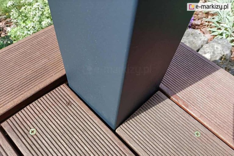 Podpora pergoli Tako w kolorze antracytowym przymocowana do betonowego podłoża i obudowana deskami tarasowymi w kolorze ciemnego brązu.